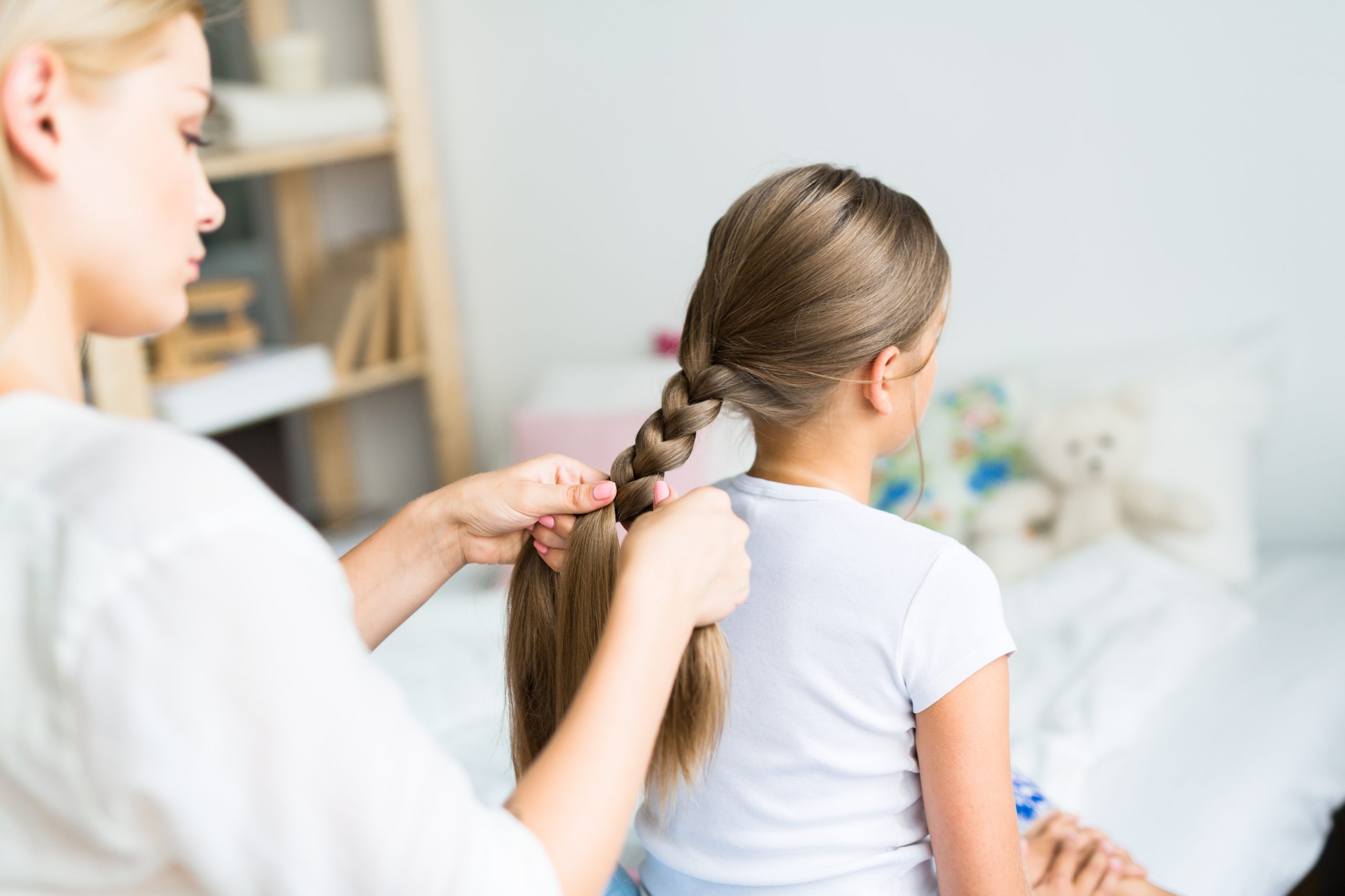Parent braiding a child's long hair, representing lice treatment questions for long, thick, or textured hair.