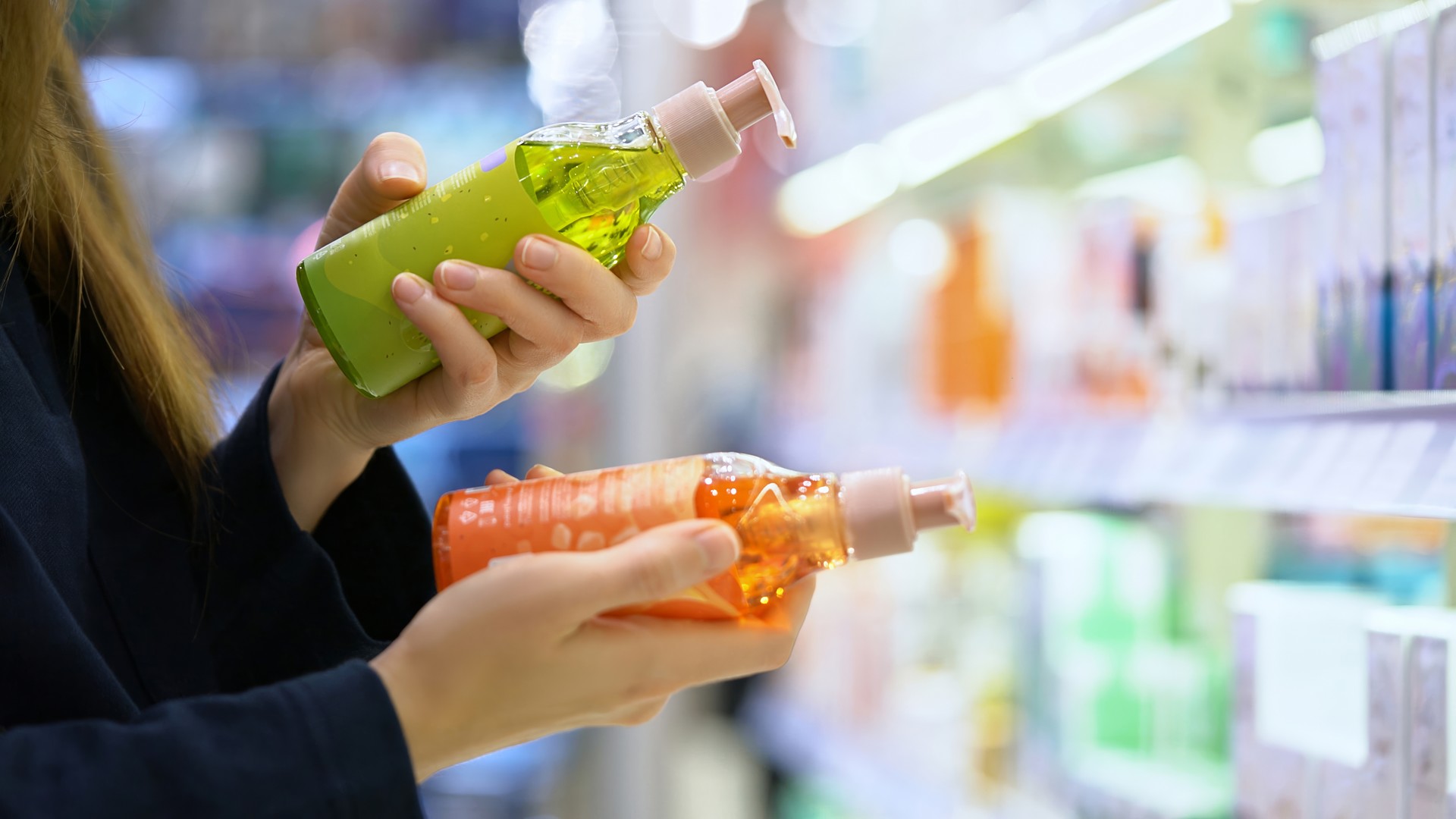 Person comparing shampoo bottles in a store aisle, matching questions about dog shampoo, pets, and why human head lice do not live on pets.