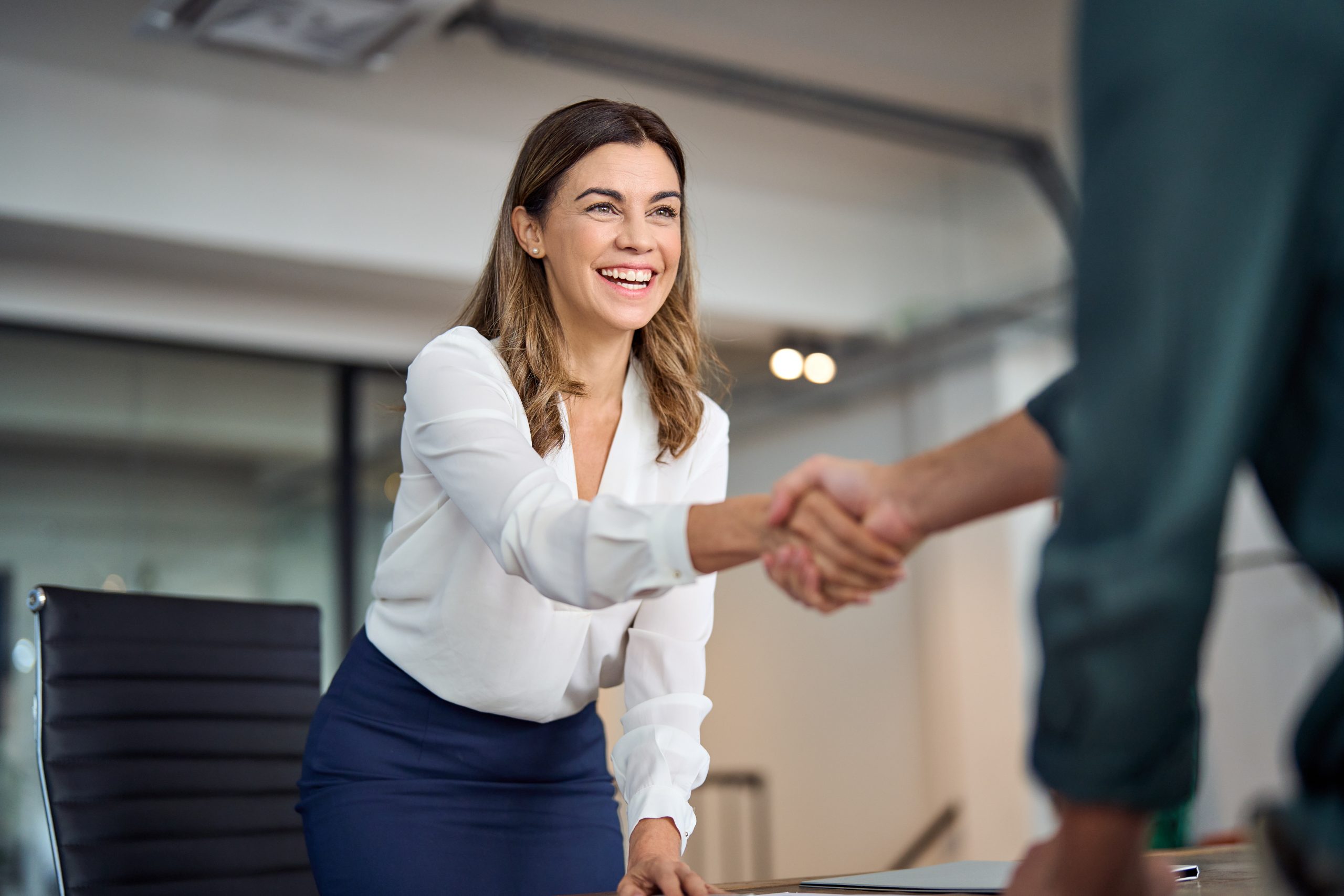 Two adults greeting each other in an office-style conversation, representing a calm respectful talk with another parent about lice exposure.