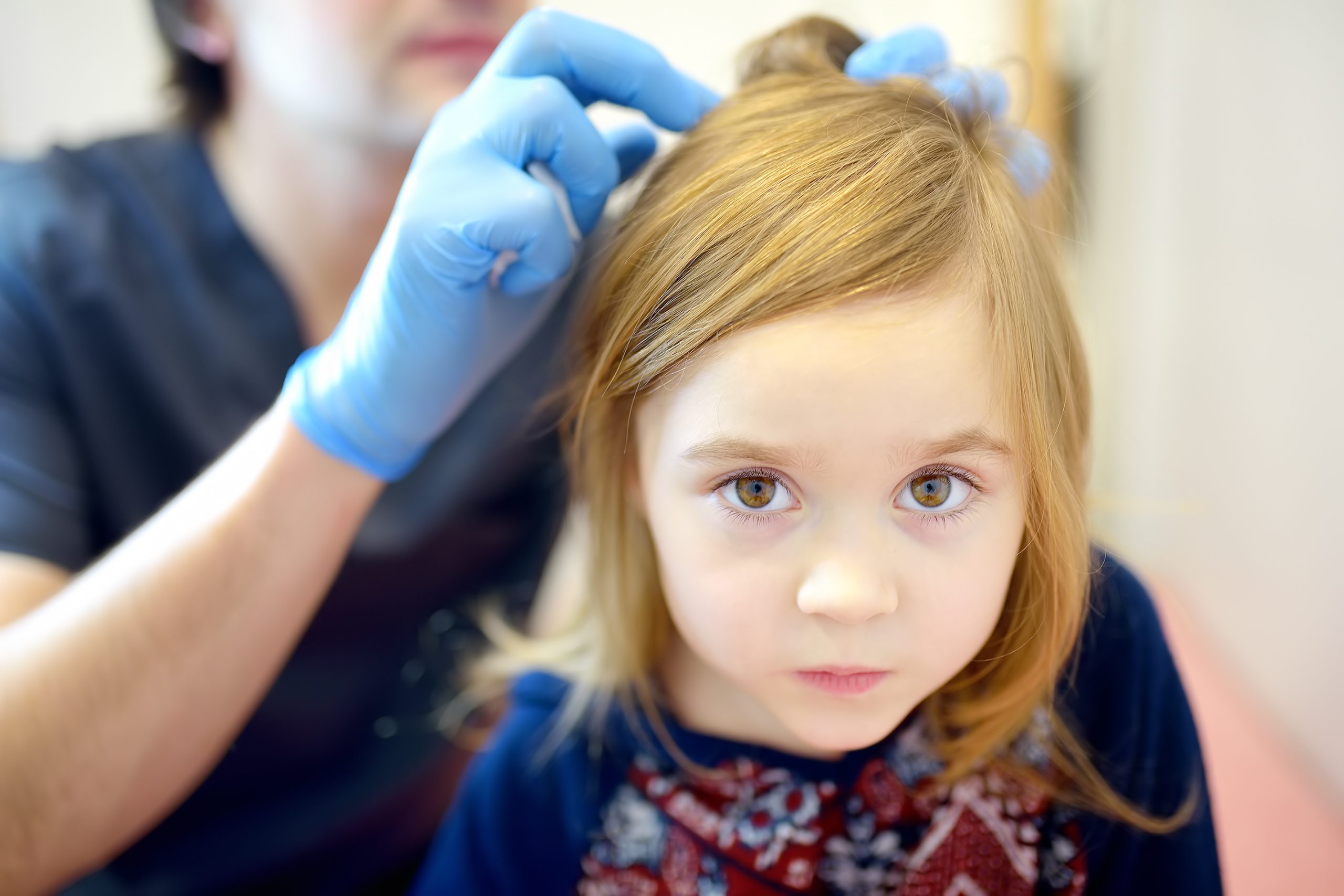 Clinician carefully examining a child's scalp during a professional lice treatment appointment.