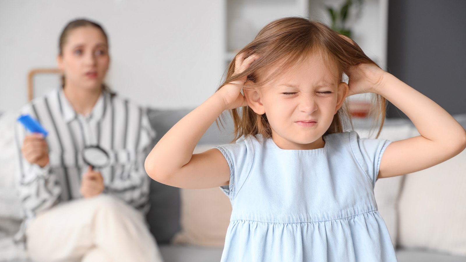 A young girl scratching her itchy scalp at home after head lice